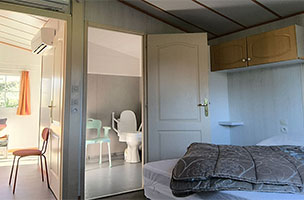 Chambre, pièce de vie et salle d’eau avec WC privatif, du chalet PMR 2 chambres 4 personnes. Location vacances au camping à l’Abri de l’Océan à Baye en Bretagne