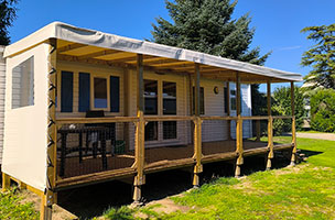 Vue du mobil-home Premium 3 chambres 6 personnes avec terrasse mini 6x2.5 m couverte équipée d’un salon de jardin, en location au camping à l’Abri de l’Océan, proche de Moëlan sur Mer.